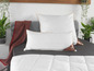 Twee witte kussens op een bed met een dekbed.