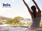 Une femme au lit, s'étire avec vue sur la ville, avec le logo BeCo.