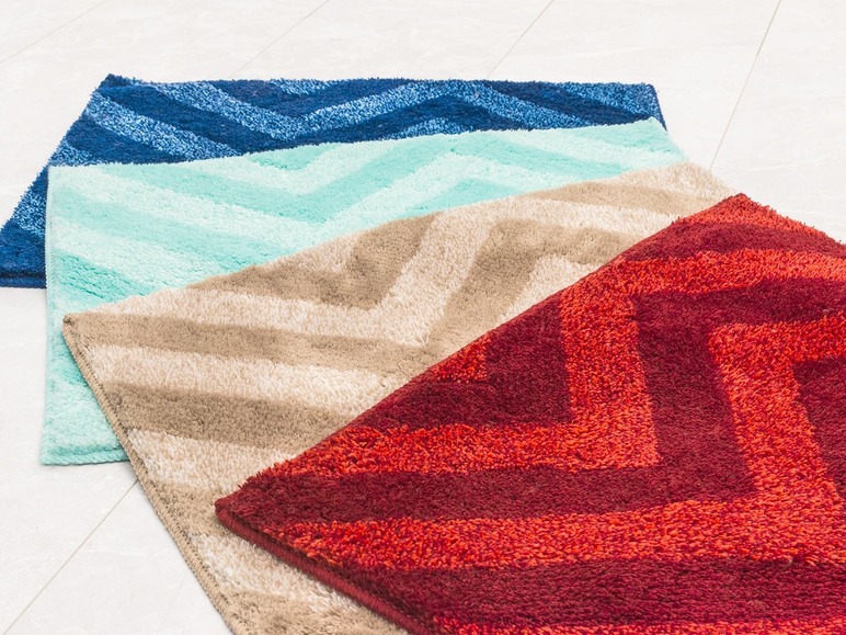 Vier badmatten met chevronpatroon in rood, beige, lichtblauw en donkerblauw.