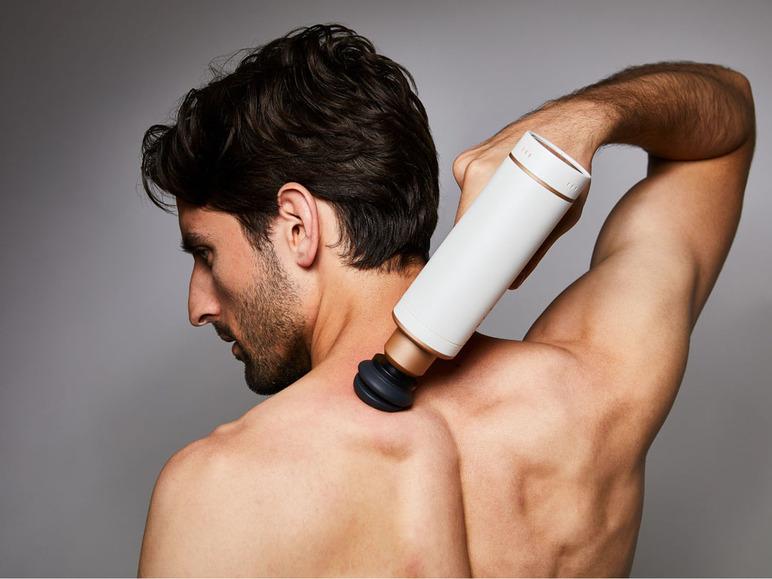 Een man gebruikt een Theragun massagepistool op zijn rug.