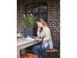Een vrouw leest een magazine aan een tafel met een plant in een zwarte pot.