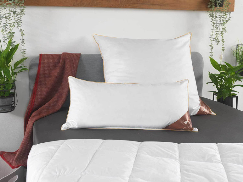 Twee witte kussens op een bed met een dekbed.