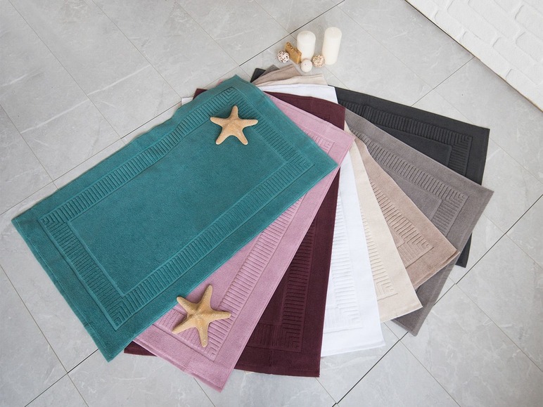 Tapis de bain de différentes couleurs, dont turquoise, rose et rouge foncé.