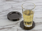 Un verre avec une boisson sur un dessous de verre noir.