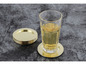 Un verre avec une boisson sur un dessous de verre doré et une pile de dessous de verre dorés.
