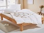 Une couette et des oreillers blancs sur un cadre de lit en bois.