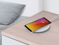 Un smartphone sur un chargeur sans fil sur une table en bois.