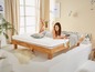 Une femme est allongée sur un lit en bois avec un matelas et une couverture.