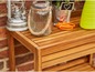 Een houten tafel met een lantaarn, glazen pot en tuingereedschap.