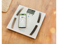 Une balance digitale avec un smartphone affichant les résultats de l'application HealthForYou.