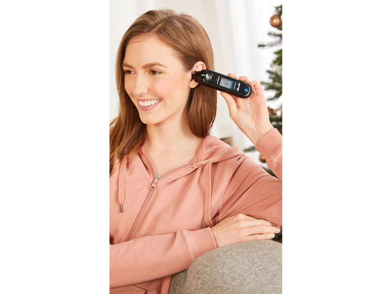 Een vrouw gebruikt een oorthermometer om haar temperatuur te meten.
