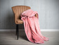 Een roze fleece deken op een bruine stoel