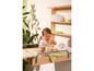 Een baby op een commode met een plank erboven met luiers en andere babyproducten.