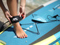 Een vrouw bevestigt een leash aan haar enkel op een supboard van Aqua Marina.