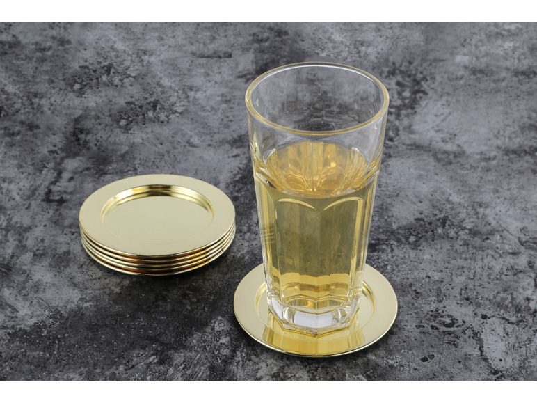 Een glas met drank op een gouden onderzetter en een stapel gouden onderzetters.