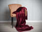 Een rode fleece deken op een bruine stoel.