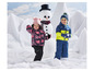 Deux enfants en vêtements d'hiver jouant dans la neige avec un bonhomme de neige.