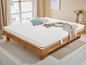 Un matelas blanc sur un cadre de lit en bois avec un tapis beige