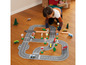 Un enfant joue avec une route en bois, des voitures et des panneaux de signalisation.