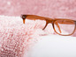 Une paire de lunettes marrons sur un tapis rose en fourrure.