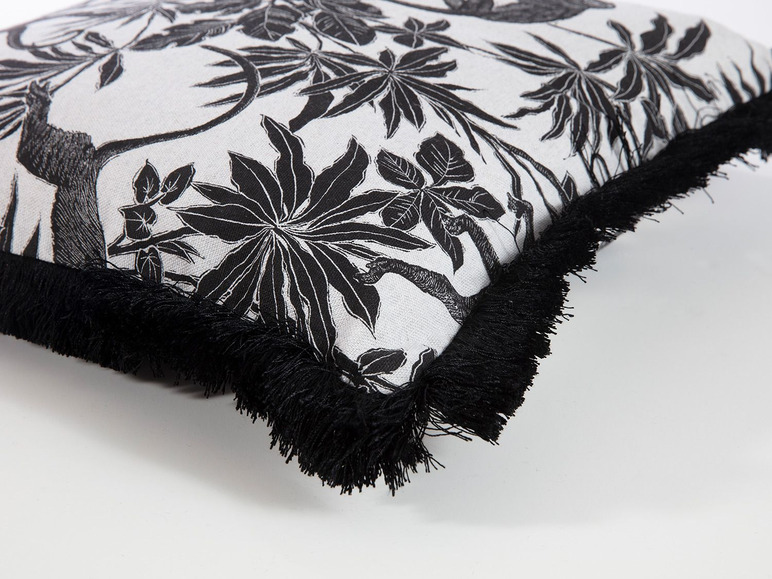 Een wit kussen met zwarte jungleprint en zwarte franjes.