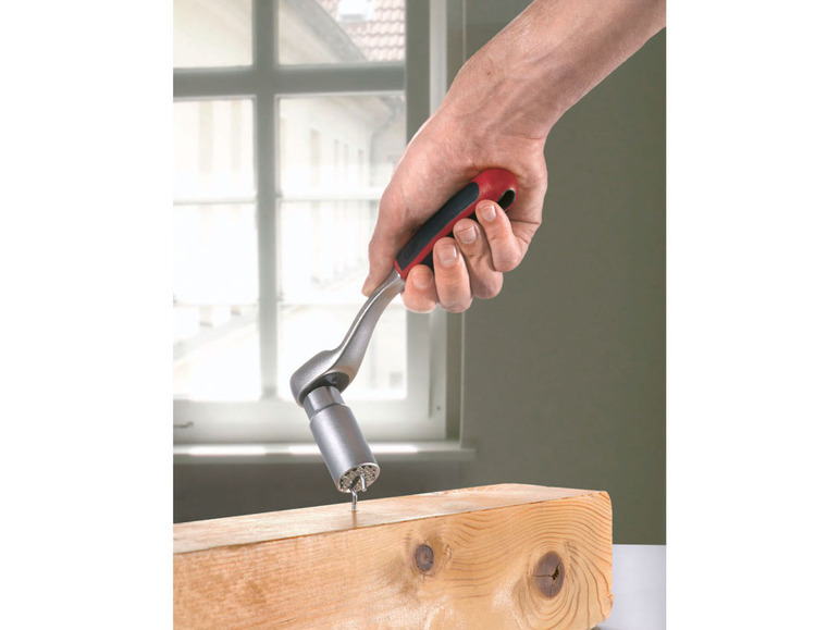 Een hand die een ratel met een bitset gebruikt om een schroef in een houten plank te draaien.