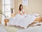 Une femme au lit avec une couette et un oreiller blancs