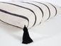 Un coussin rayé avec une frange noire.