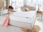 Een wit matras met een beige hoofdeinde en een roze deken.