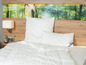 Une couette blanche avec un oreiller Beco sur un lit avec une tête de lit en bois.