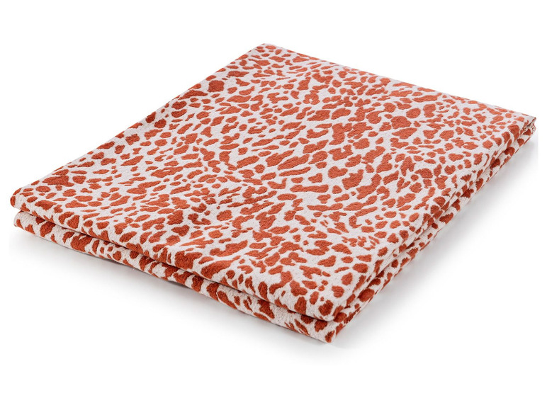 Une couverture en laine orange pliée avec un motif léopard.
