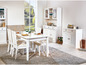 Witte eettafel met stoelen, dressoir en vitrinekast in een eetkamer.