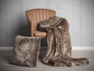 Een bruine fauteuil met een pluche deken en kussen