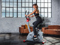Een vrouw die fietst op een hometrainer in een moderne woonkamer.