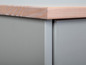 Een grijs dressoir met een houten blad.
