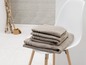 Pile de serviettes beiges sur une chaise blanche