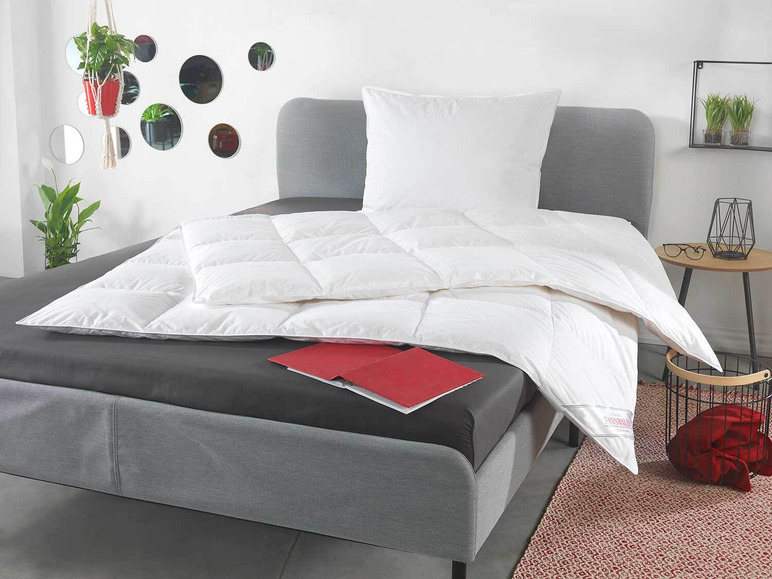 Une couette et un oreiller blancs sur un lit gris.