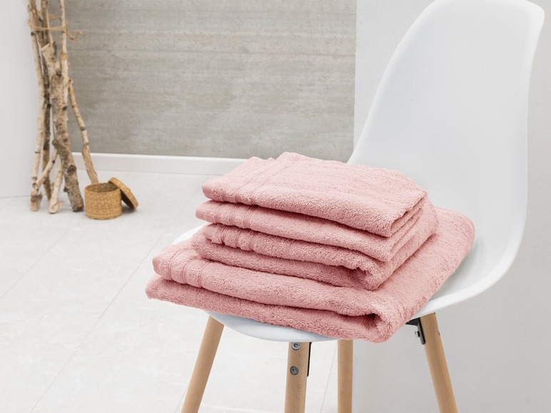 Une pile de serviettes roses sur une chaise blanche.