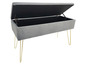 Un banc de rangement en velours gris avec des pieds dorés.