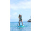 Een vrouw peddelt op een opblaasbaar paddleboard in turquoise water.