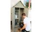 Man putting gardening tools in a wooden shed.