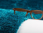 Un tapis en fourrure bleu et des lunettes à monture marron.
