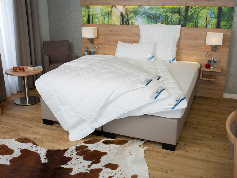 Een bed met een witte dekbed van Beda en een wit kussen.