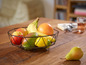 Een zwarte fruitmand met bananen, een grapefruit, een mango, een citroen en appels.
