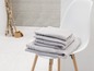 Une pile de serviettes grises sur une chaise blanche.