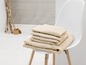 Serviettes de bain beiges empilées sur une chaise blanche.