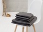 Une pile de serviettes de bain gris foncé sur une chaise blanche.