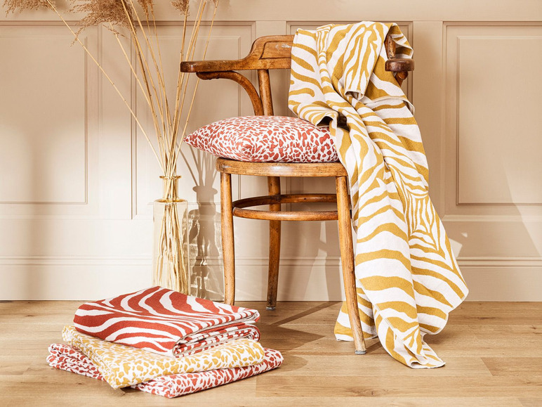 Une chaise avec une couverture rayée, un coussin et des couvertures rayées sur le sol.