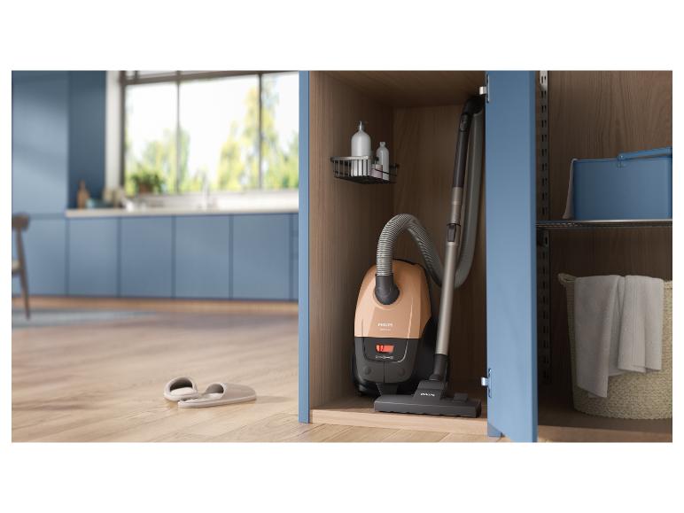 Aspirateur rangé dans un placard, des pantoufles sur le parquet d'une cuisine.
