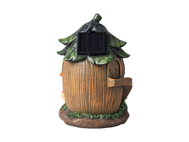 Décoration de jardin en forme de maison de fée avec un panneau solaire sur le toit.